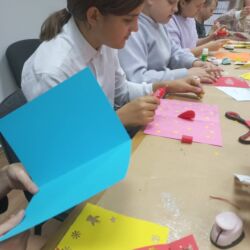 Wolontariusze wykonują kartki swiąteczne dla podopiecznych Fundacji ,,Okno Nadziei"